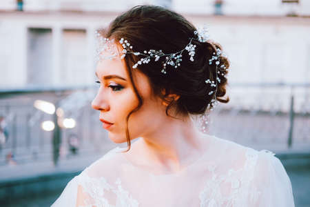Happy young bride in flowing white dress enjoying herself outdoors. Bridal makeup and hairstyle.