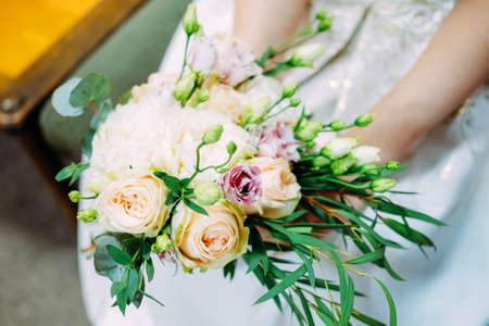 Young caucasian woman holding bouquet of fresh flowers made of roses, eustoma flowers and green leaves. Summer family event.の写真素材