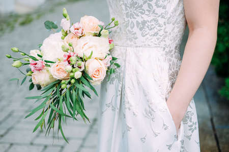 Young caucasian woman holding bouquet of fresh flowers made of roses, eustoma flowers and green leaves. Summer family event.の写真素材