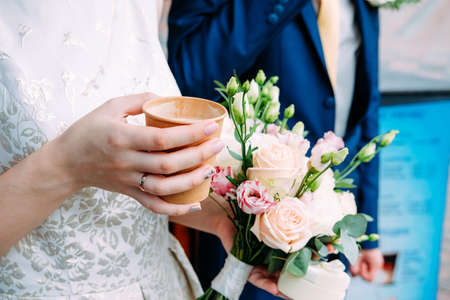 Husband and wife in blue suit and wedding dress getting married and holding hands and drinking coffeeの写真素材