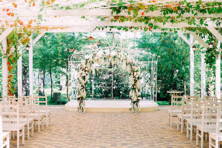 Getting ready for the wedding ceremony. Wedding arch decorated with white flowers and chairs for the guests.の写真素材
