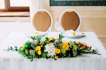 Elegant bride and groom table setting for the wedding with candlestick centerpiece in yellow and green colorsの写真素材