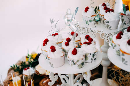Sweet tasty cupcakes with white icing topped with raspberriesの写真素材