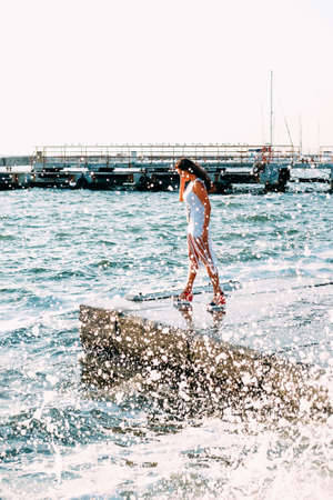 Happy smiling woman in her thirties in white dress walking on the pierの写真素材