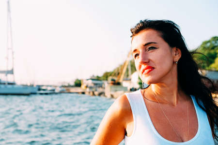 Happy smiling woman in her thirties in white dress walking on the pier