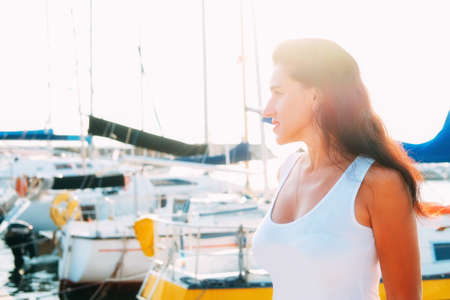 Happy smiling woman in her thirties in white dress walking on the pierの写真素材