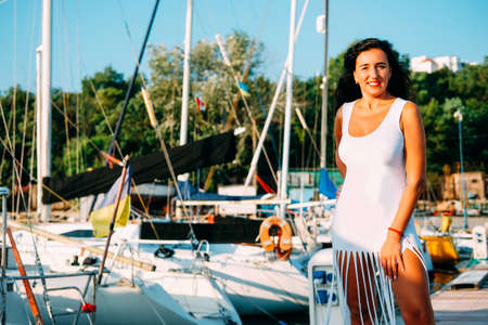 Happy smiling woman in her thirties in white dress walking on the pierの写真素材