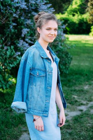 Cute stylish young woman wearing denim jacket, black leggins and high heel sandals