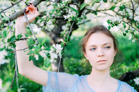Calm and pretty young woman in the garden wearing transparent blue dressの写真素材