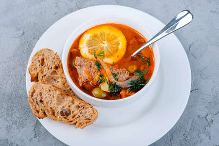 Solyanka a thick vinegary soup of vegetables and beef meat served with lemon and olives