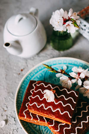 Sweet sunday dessert. Chocolate brownies with black tea on table decorated with flowers and candles.