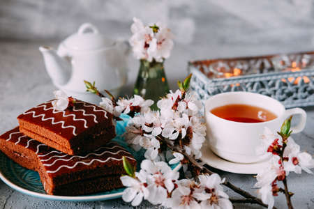 Sweet sunday dessert. Chocolate brownies with black tea on table decorated with flowers and candles.の写真素材