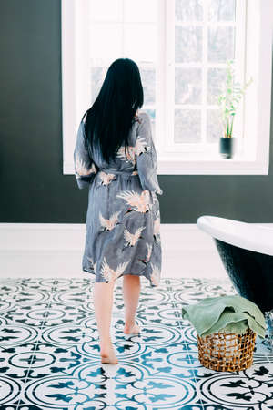 Young brunette with long black hair and green eyes getting ready in her bathroom. Intimacy concept.