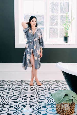 Young brunette with long black hair and green eyes getting ready in her bathroom. Intimacy concept.