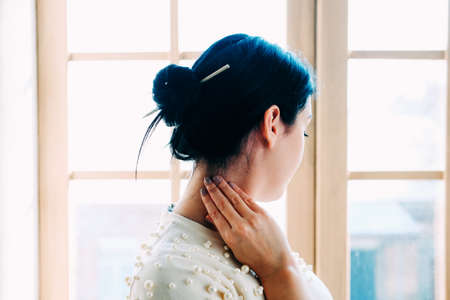 Young student woman in the class with a pencil in the hair bun. View from the back.の写真素材