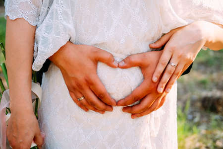 Newly married couple of lovers hugging and touching the belly walking outdoors