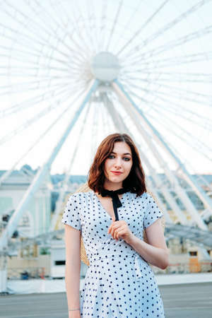 Cute caucasian brunette in white dress walking alone in the streets in downtownの写真素材