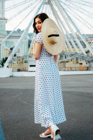 Cute caucasian brunette in white dress walking alone in the streets in downtownの写真素材