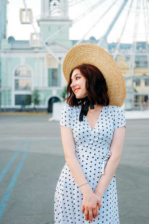 Cute caucasian brunette in white dress walking alone in the streets in downtownの写真素材
