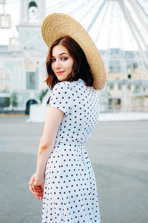 Cute caucasian brunette in white dress walking alone in the streets in downtownの写真素材