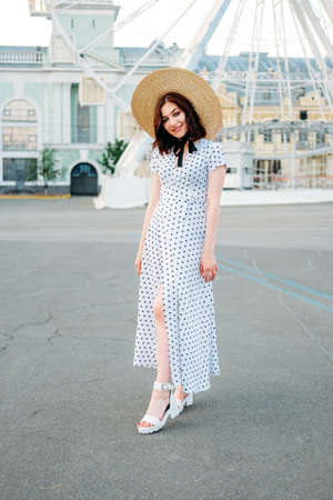 Cute caucasian brunette in white dress walking alone in the streets in downtownの写真素材