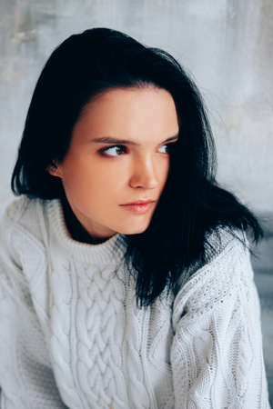 Brunette in white minimalist outfit. Winter knitted sweater.の写真素材