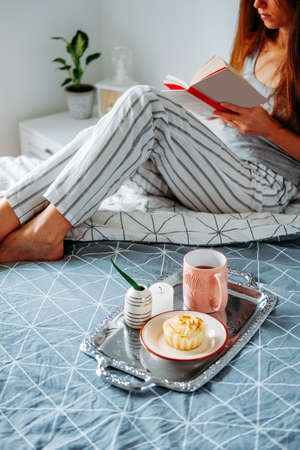 Morning snack. Cottage cheese muffin and tea. Early breakfast. Girl reaging in her bed.の写真素材