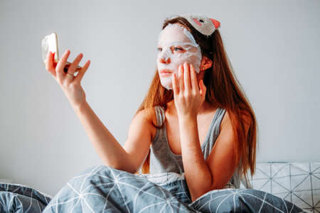 Indoor home beauty procedures. Woman wearing sleeping mask and moisturizing mask getting ready in the morning.の写真素材