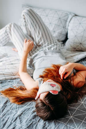 Sleeping habits. Woman in sleeping mask laying on the bed. Insomnia.の写真素材