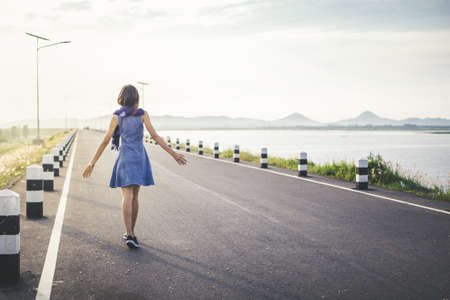 Happy young woman walking on the roadの写真素材