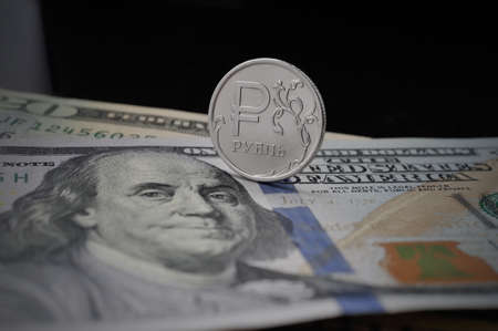 russian ruble coin on a hundred dollars banknote background