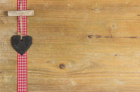 Slate heart lies on a red border  Behind an old wooden board の写真素材