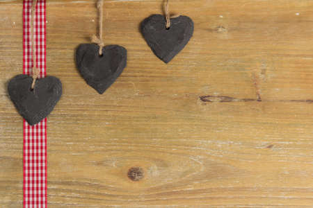 Slate heart lies on a red border  Behind an old wooden board の写真素材