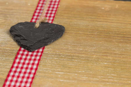 Slate heart lies on a red border  Behind an old wooden board の写真素材