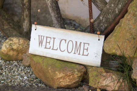 Welcome sign balanced on rocks at the side of a foot path in the garden to greet guests as they enter the propertyの写真素材
