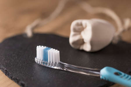 New blue toothbrush with the mold of a tooth in the background lying on a black mat with selective...