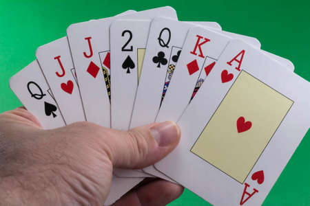 Hand holding a royal flush hearts on green