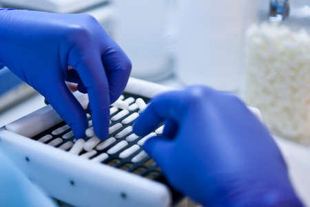 Packing white capsules in a sorting machine in a pharmaceutical laboratory, Spainの写真素材