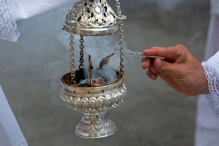 Altar boy looking with a silver spoon incense in a censer during a procession of holy week, Andalucia, Spainのeditorial素材