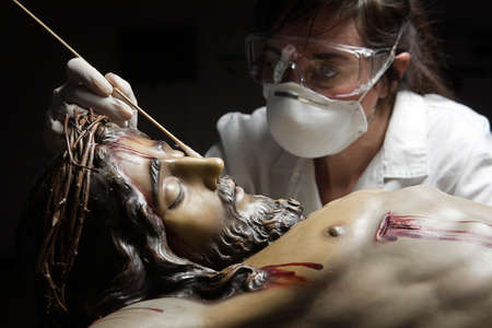 Cleaning of the face of a wooden sculpture of Christ crucified with an isopo impregnated with dimethylformamide, Andalusia, Spainの写真素材