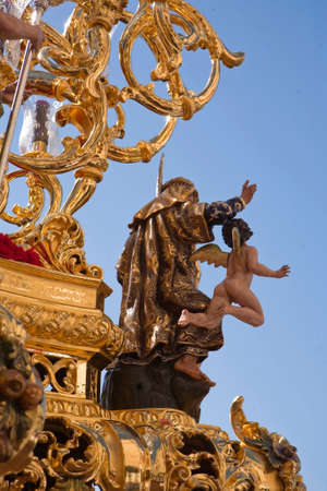 Polychromed figure in a golden throne during a procession of holy week, Seville, Spain