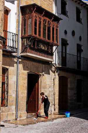 House and traditional balcony in òbeda, woman cleaning the entrance on a sunny day, òbeda, Jan province, Andalusia, Spainのeditorial素材