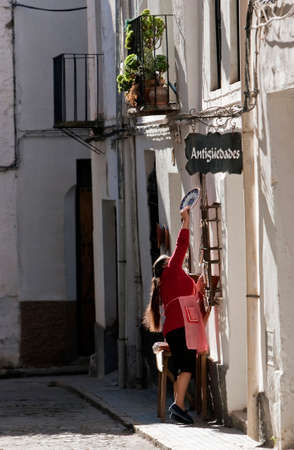 Woman hanging a ceramic plate on the door of a shop of antiques, òbeda, province Jan, Andalusia, Spainのeditorial素材