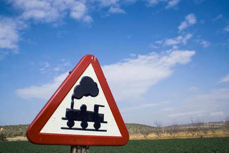Warning sign worn of level crossing without barriers, blue sky with clouds