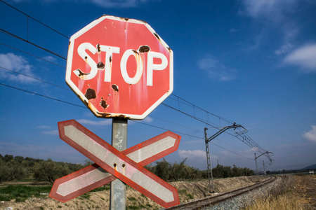 Warning sign worn of level crossing without barriers, blue sky with cloudsの写真素材