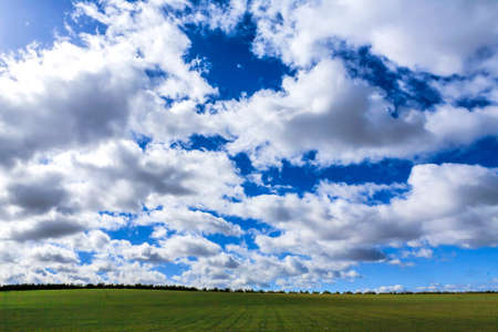 landscape with green grass, road and cloudsの写真素材