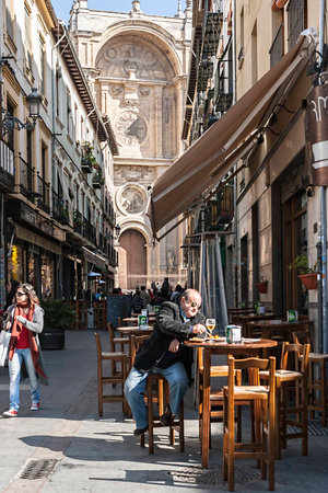  Granada, SPAIN - 16 february 2013  Man taking a snack on the street Marques with the facade of the Cathedral in the background, Granada, Spainのeditorial素材