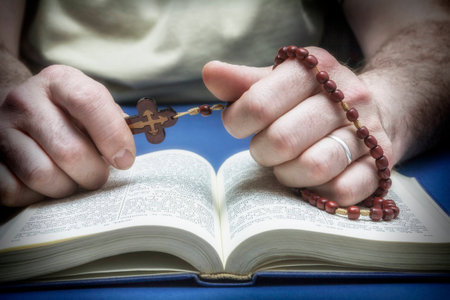 Christian believer praying to God with rosary in handの写真素材