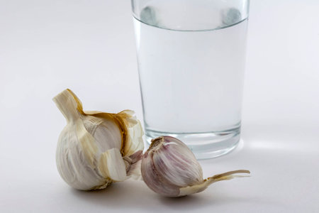 Glass of water and some garlic isolated on white backgroundの写真素材