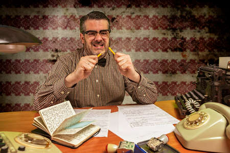 angry office worker breaks yellow pencil in the office in the 1960sの写真素材